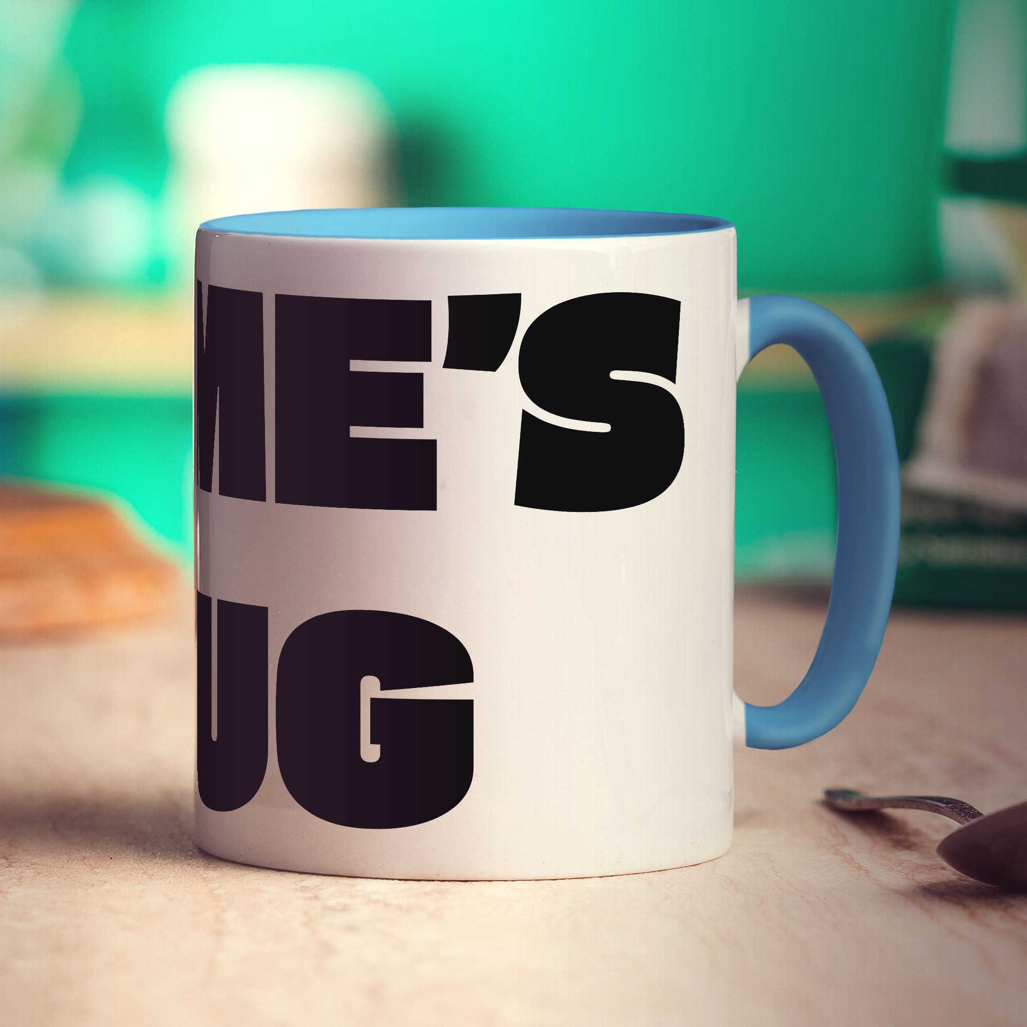 Mug with text 'NAME'S MUG' on a wooden surface with a blurred green background